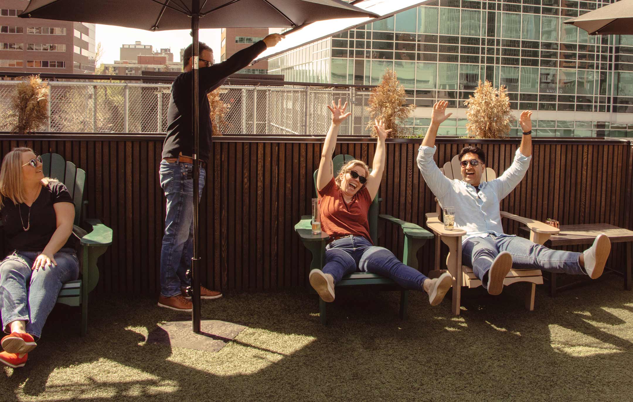 Two people raise their hands in enjoyment as they sit outside on a patio.